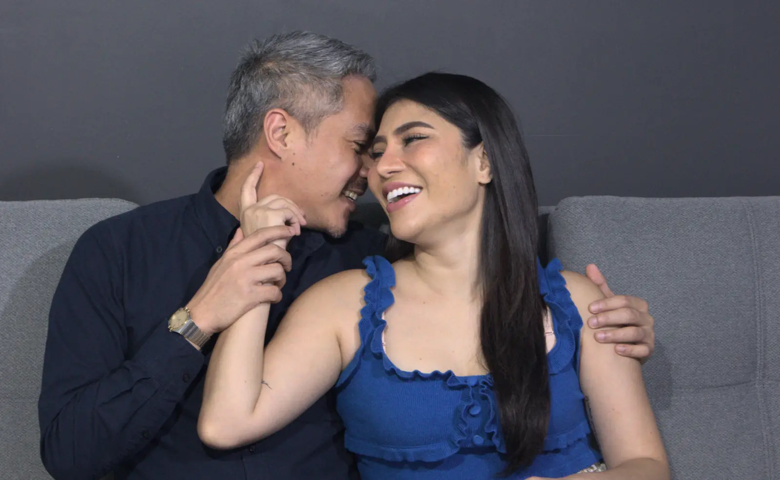 Couple on a couch giggling as they enjoy talking about tips para matagal labasan.