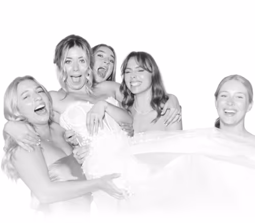 Group of five joyful young women posing closely together with big smiles and laughter.