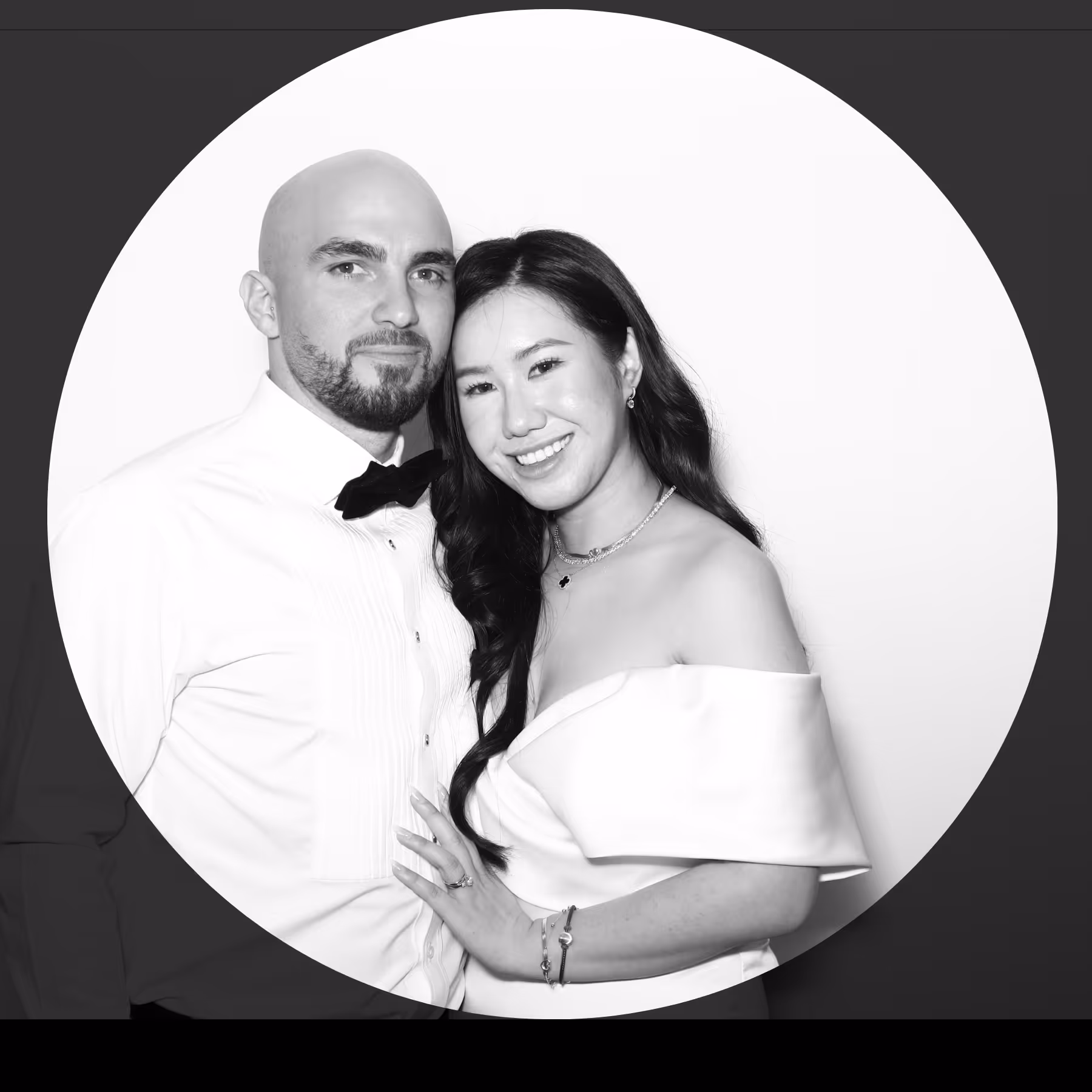 Smiling couple dressed formally, man in white shirt with bow tie and woman in off-shoulder dress with long hair.