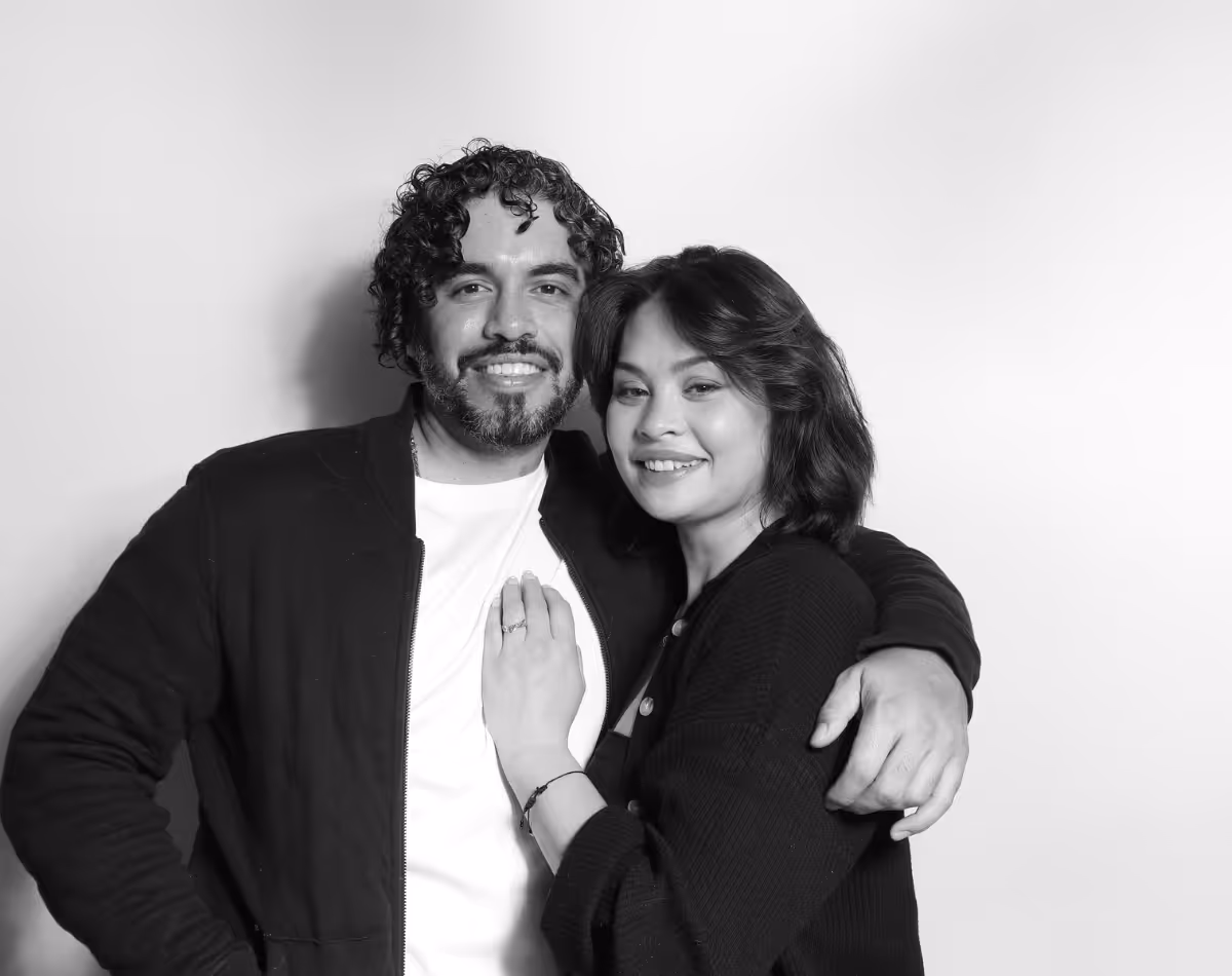 Smiling couple embracing, the woman showing a ring on her finger.