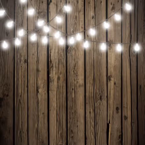 Rustic wooden plank wall with strings of glowing white string lights hanging in front.