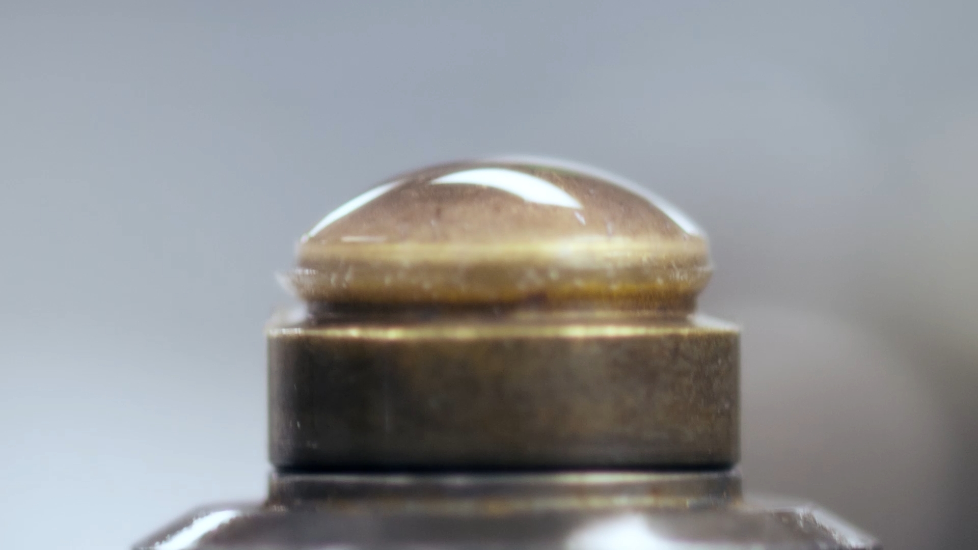 Close-up of a vintage brass perfume bottle cap with a domed top.