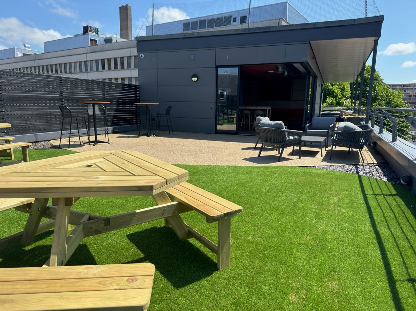 Green grass and picnic benches on the terrace of an office building. 