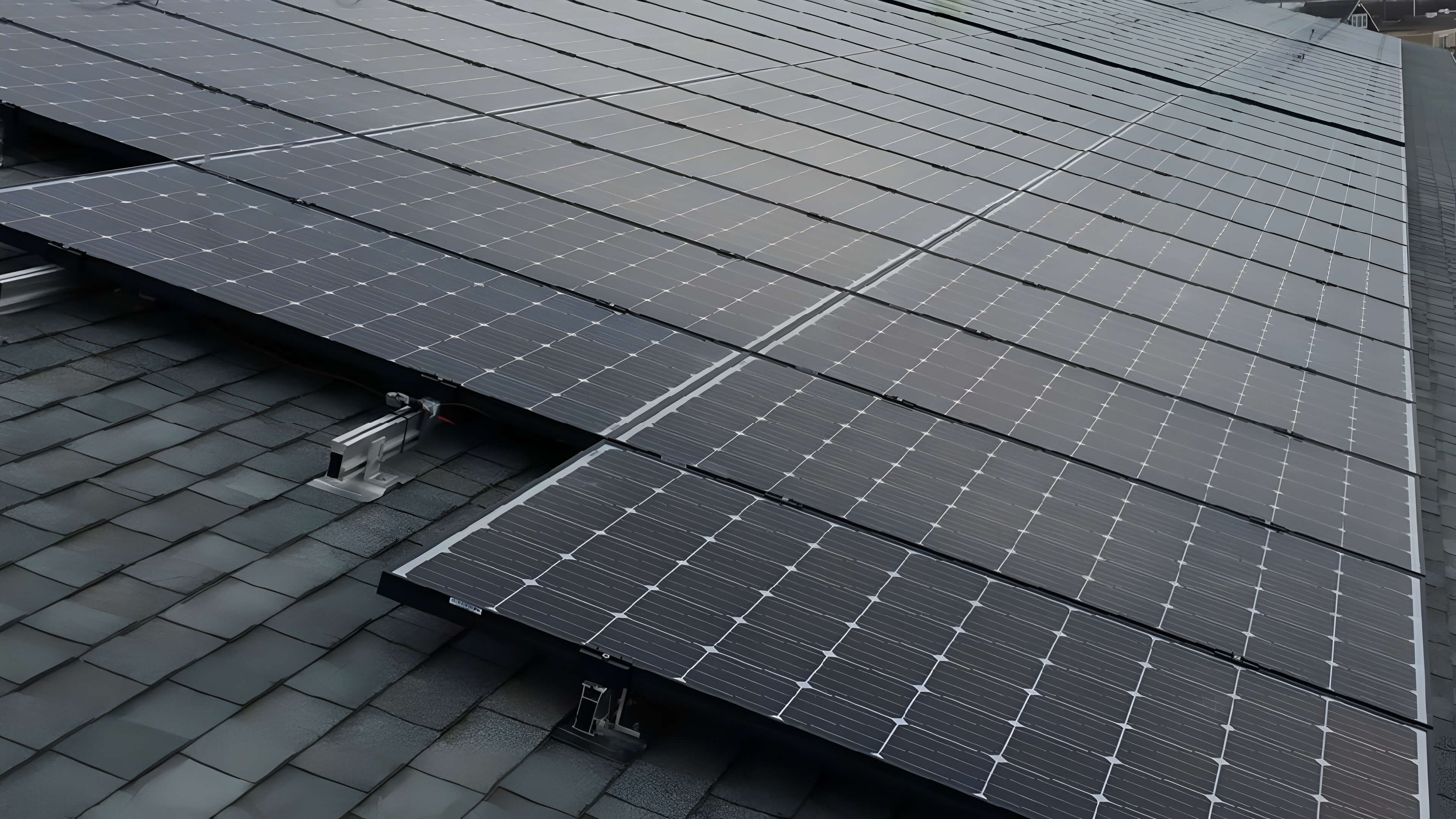 Rows of solar panels installed on a sloped roof with dark shingles.
