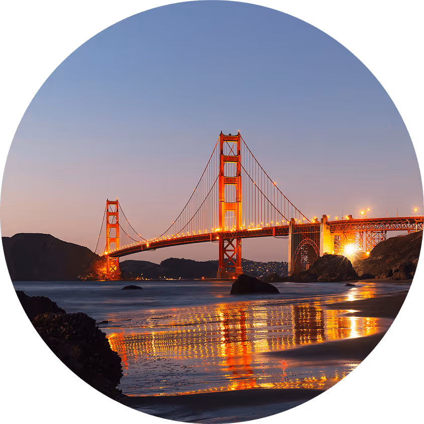 Golden Gate Bridge illuminated at dusk with its reflection in the water below.