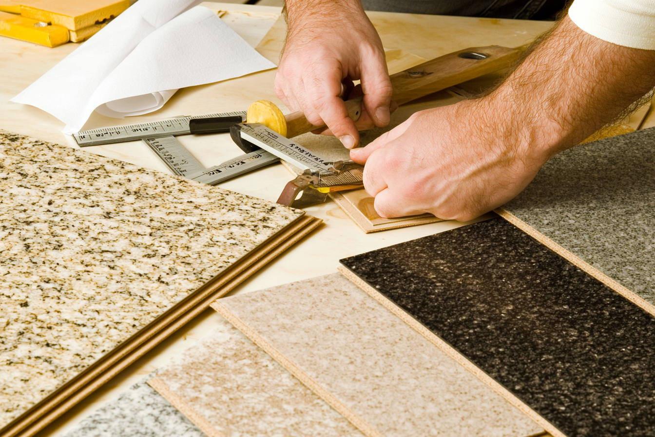 Flooring takeoff with various tile samples, measuring tools, and hand-marking dimensions for material estimation.