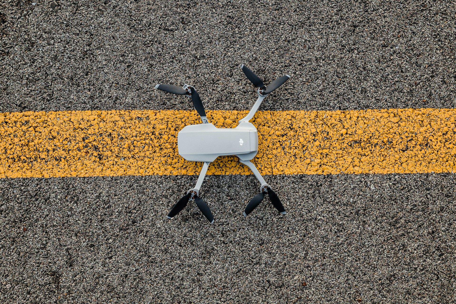 Bild einer Drohne auf einem gelb-grauen Asphaltstreifen