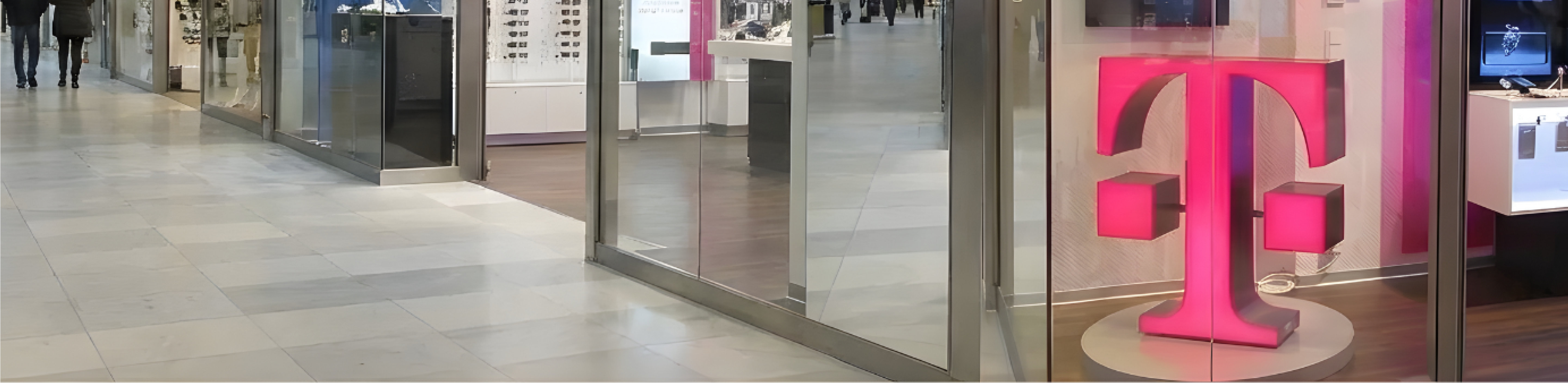 Růžové prosvětlené logo T ve výloze prodejny T-Mobile