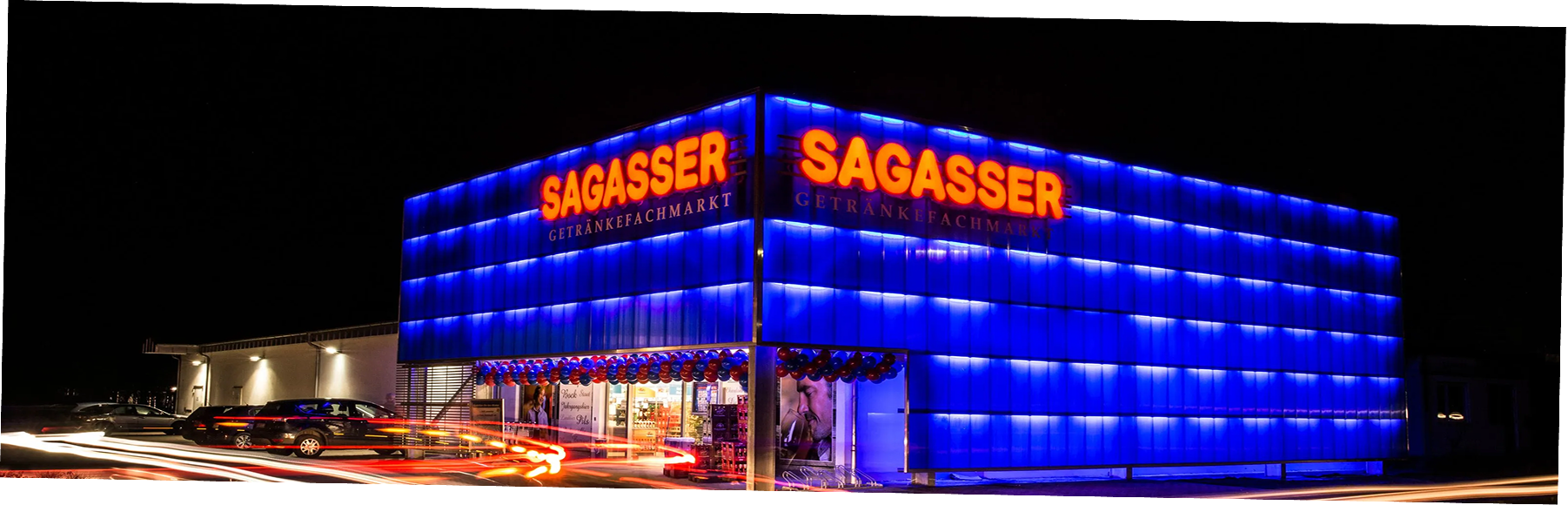Modře prosvětlená fasáda prodejny Sagasser s LED nápisem