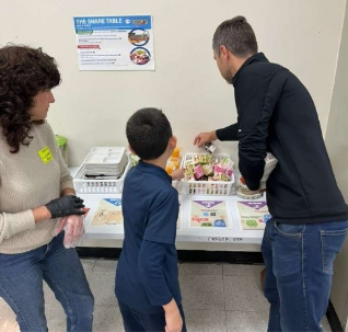A child and adult interacting with a community share table.