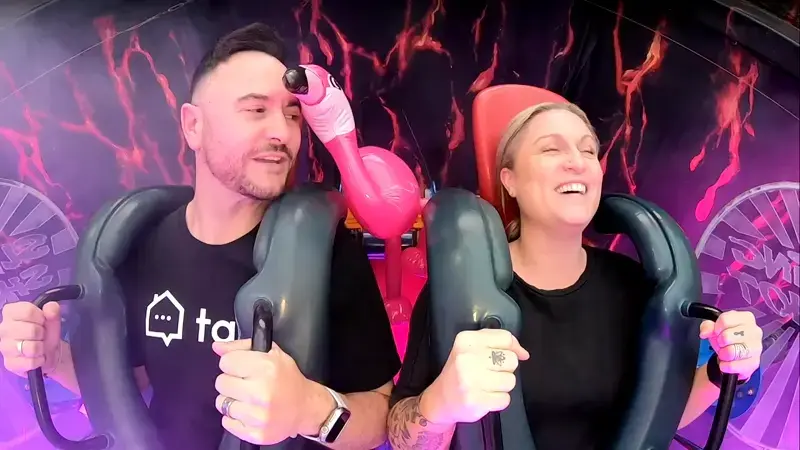 Tapi team member and customer strapped into a giant slingshot ride, smiling and laughing while recording a video testimonial.