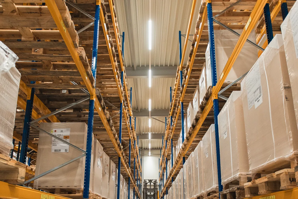 Low-angle view of a long warehouse aisle with pallet racking stacked with cartons