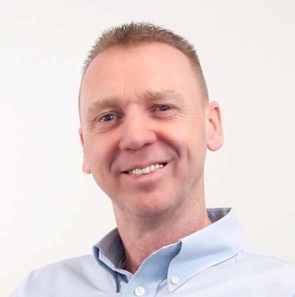 Smiling man with short hair wearing a light blue button-up shirt against a white background.