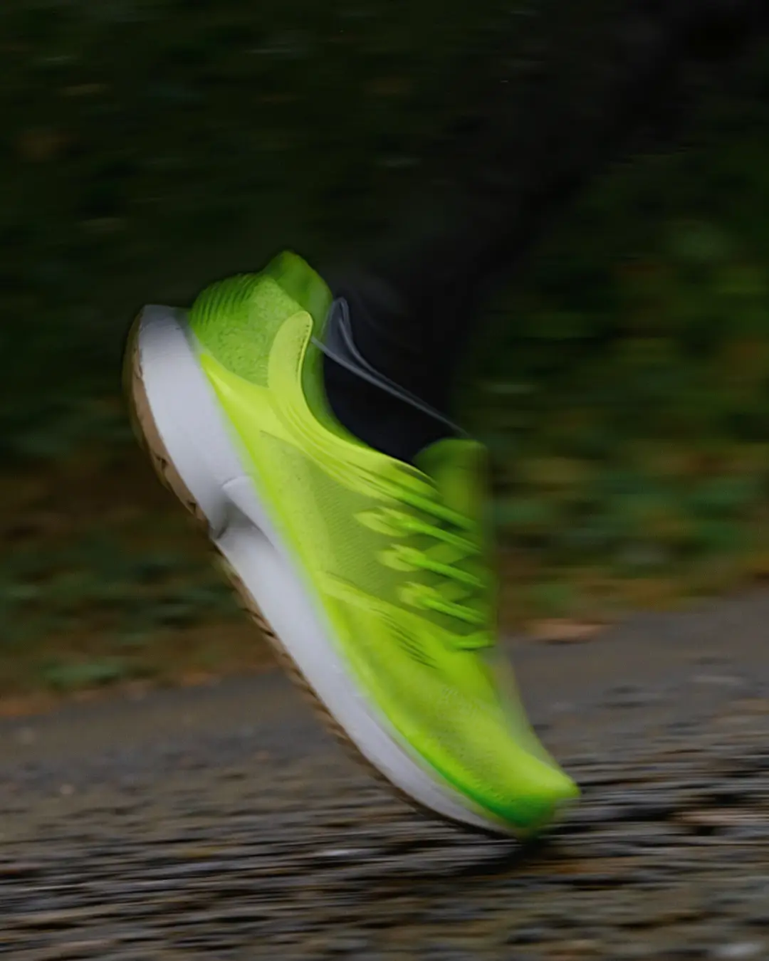 Nahaufnahme eines leuchtend grünen Laufschuhs in Bewegung auf einem nassen Asphaltweg.
