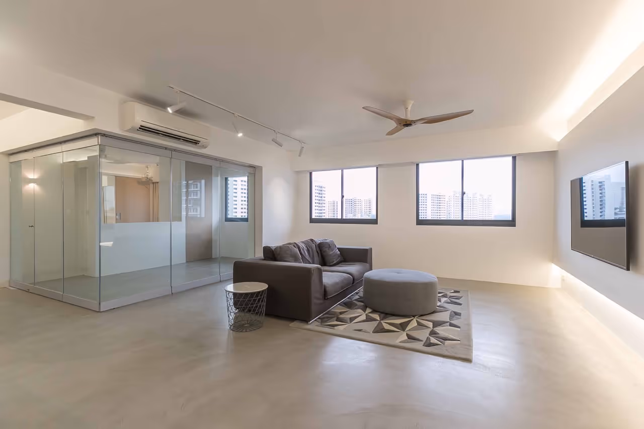 Minimalist HDB living room in Singapore with cement screed flooring, glass partition room, grey sofa, and wall-mounted TV.