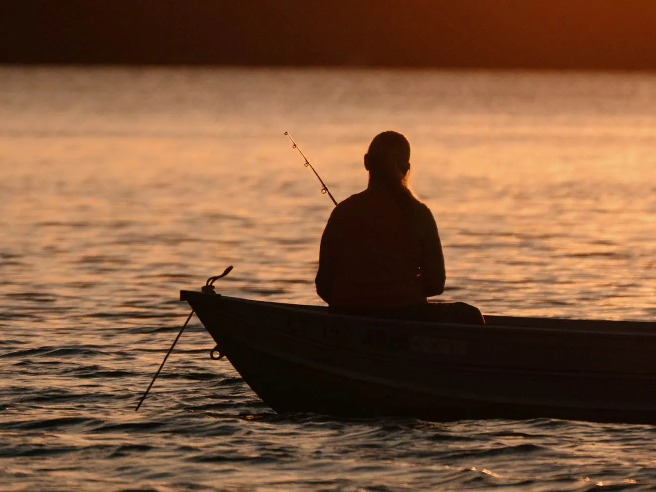 fisherman on boat at sunset