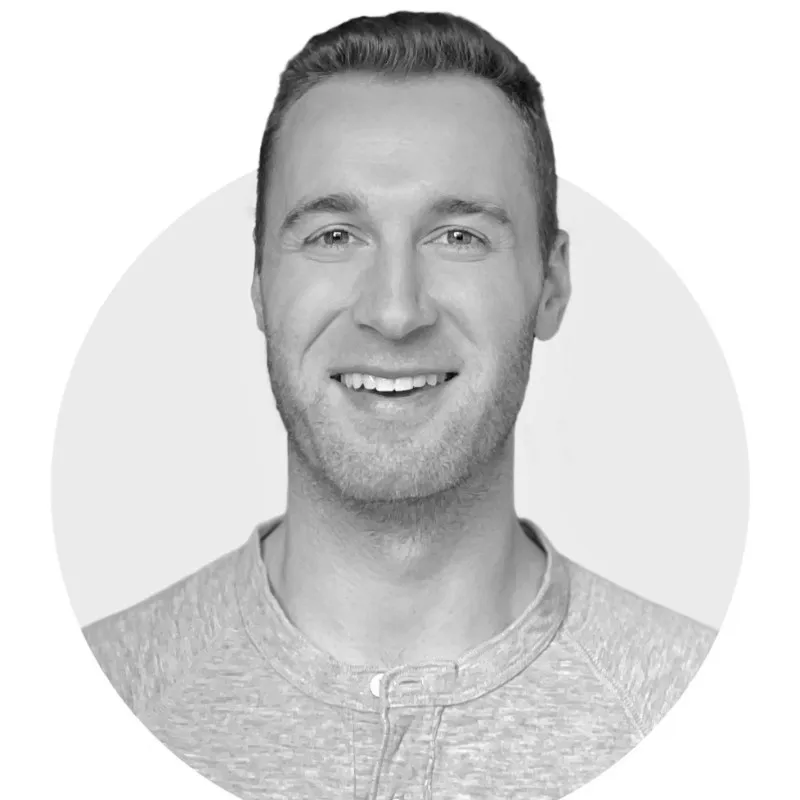 Smiling man with short hair wearing a light-colored shirt in a circular frame.