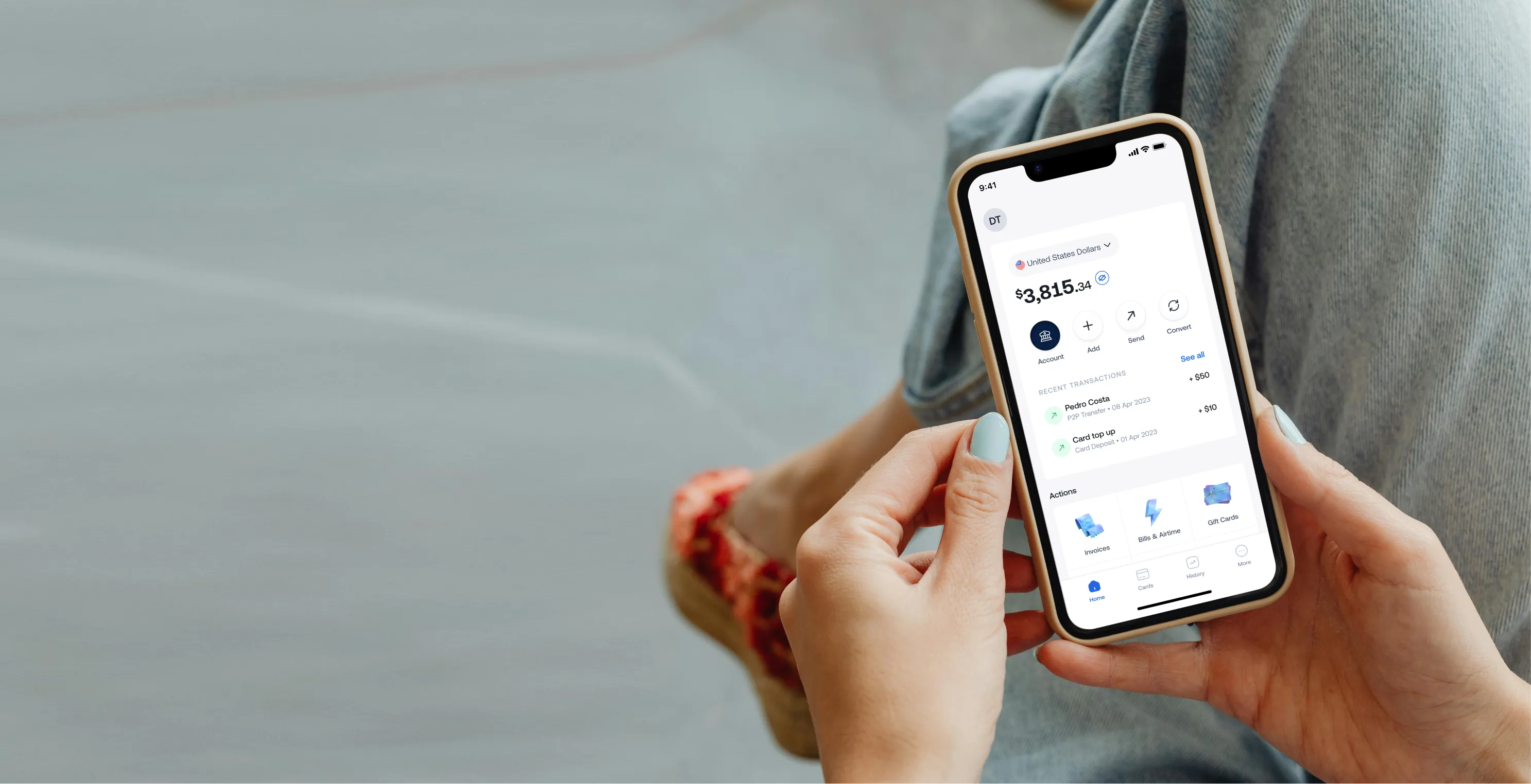 Person holding smartphone showing financial app with balance, transactions, and action icons.