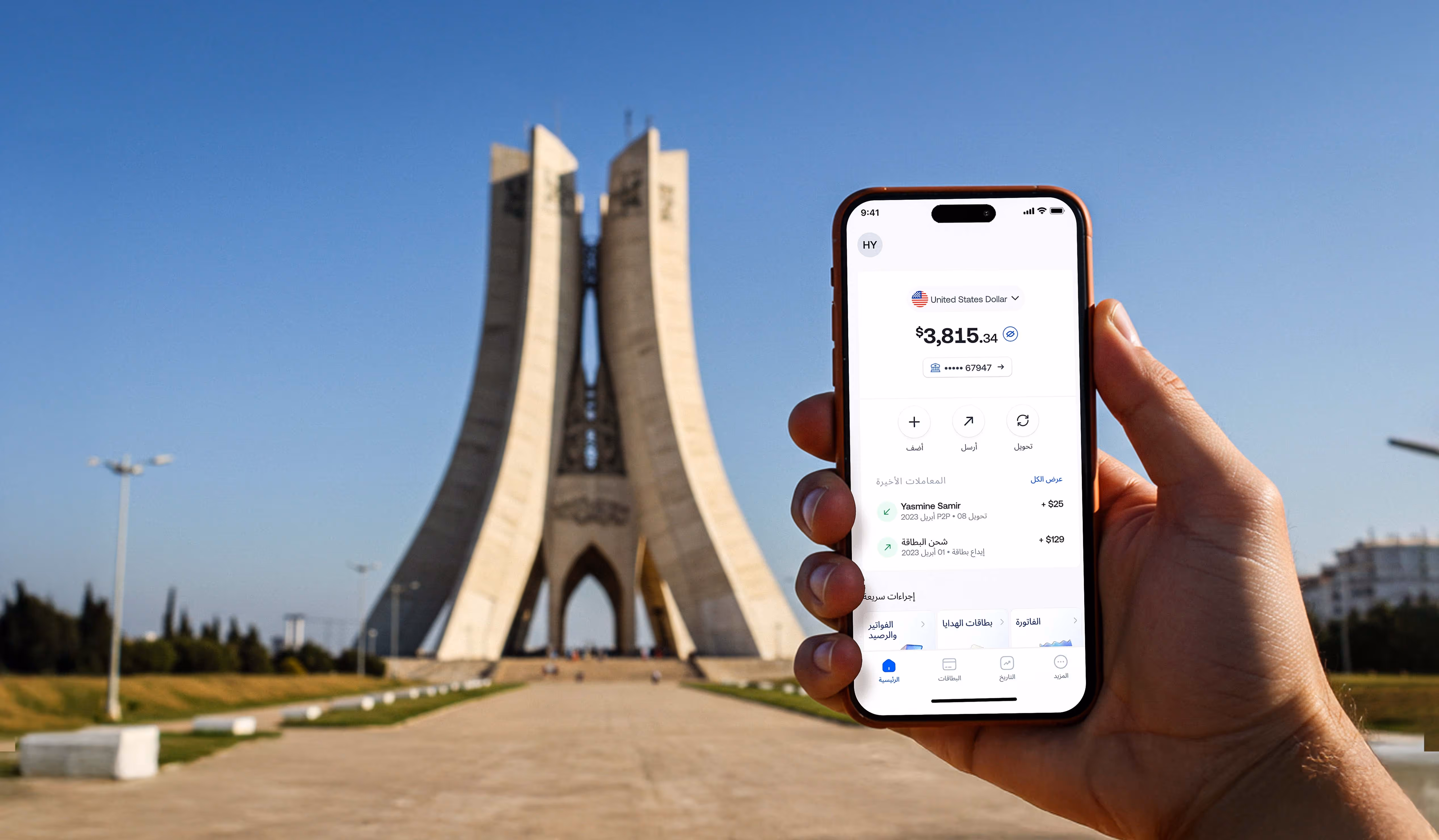 Hand holding a smartphone displaying a digital wallet app showing $3,815.34 balance with Monument in background.