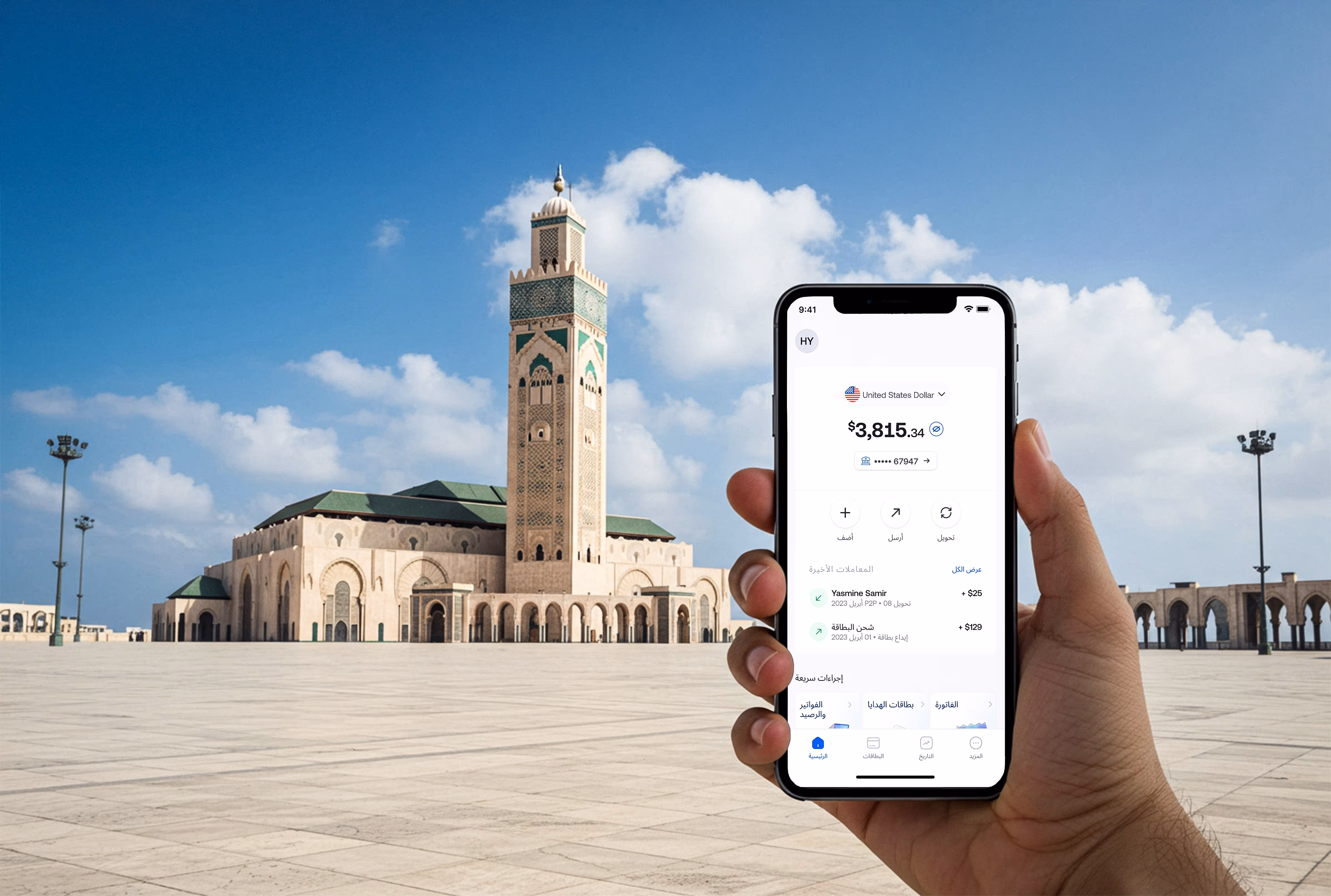 Hand holding phone showing $3,815 balance with Hassan II Mosque in Casablanca under blue sky.