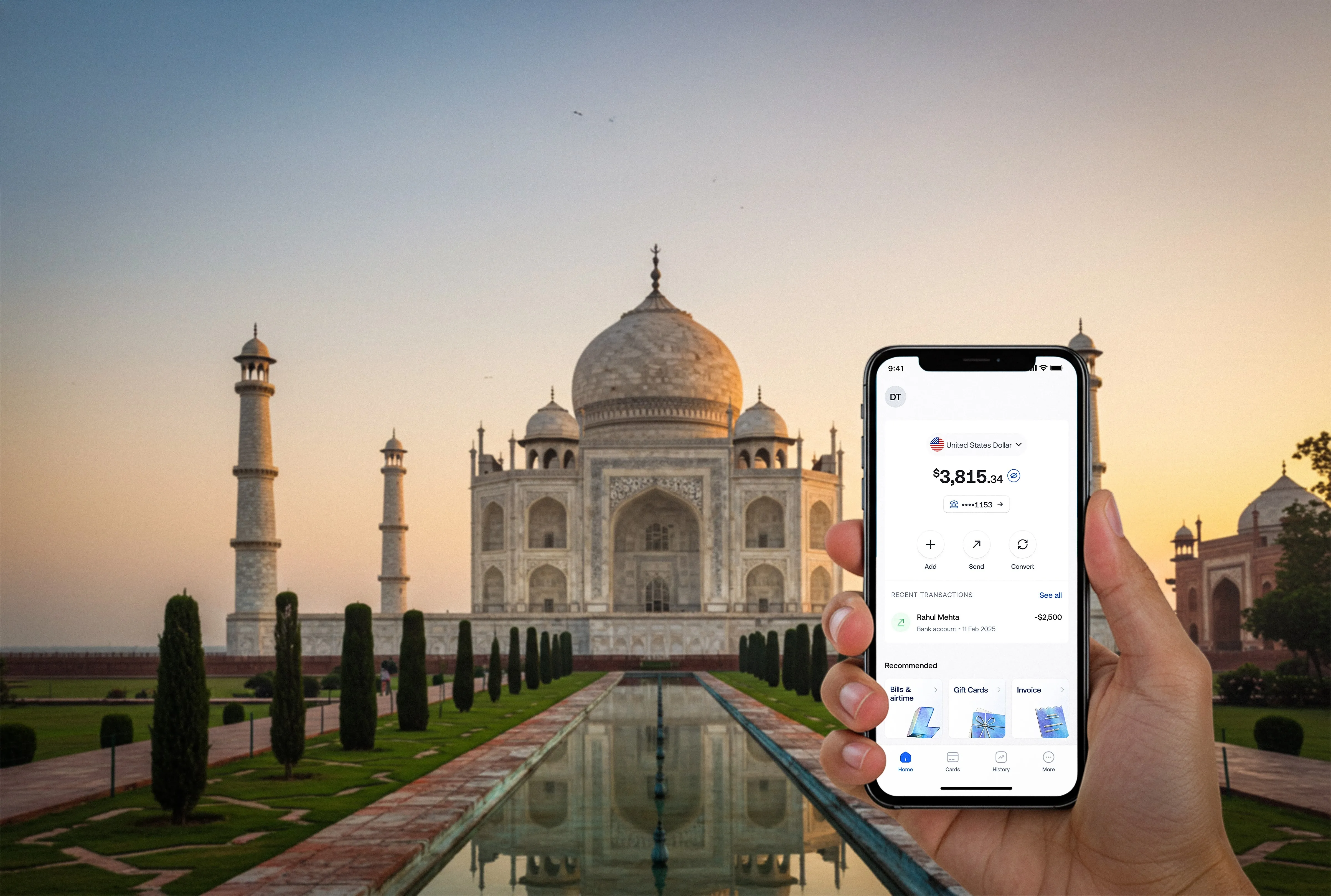 Hand holding phone with finance app showing balance $3,815 in front of the Taj Mahal at sunset.