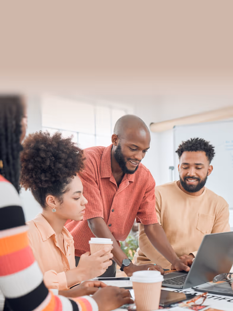 An image of five professionals discussing at a bright conference table in an office.