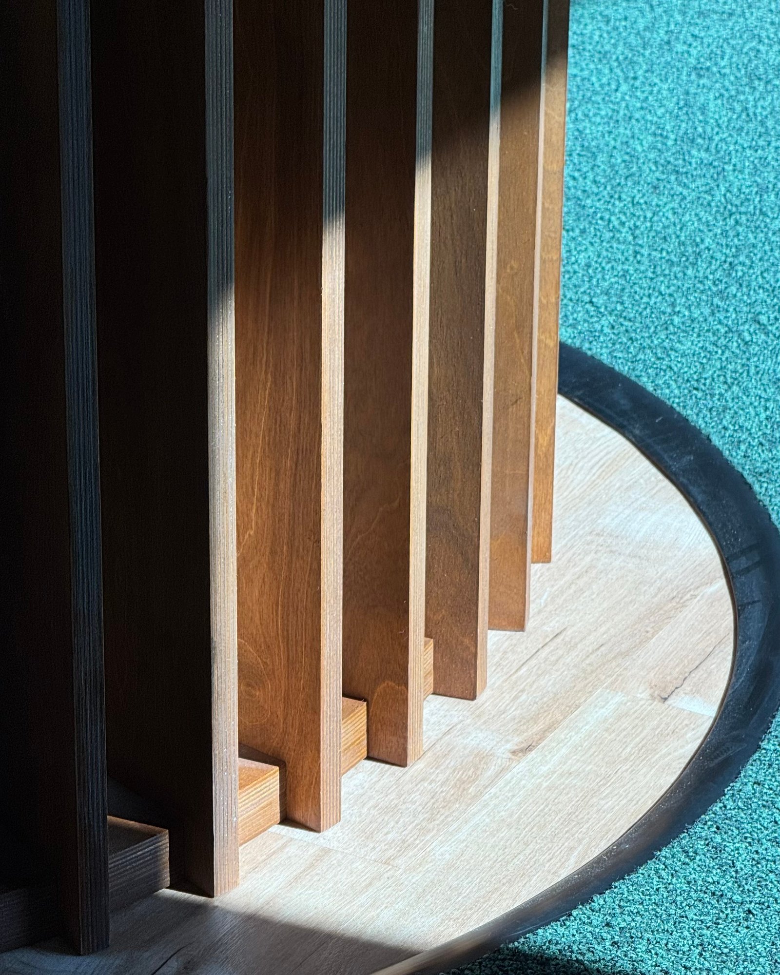 Curved wood fin column on a terrazzo base