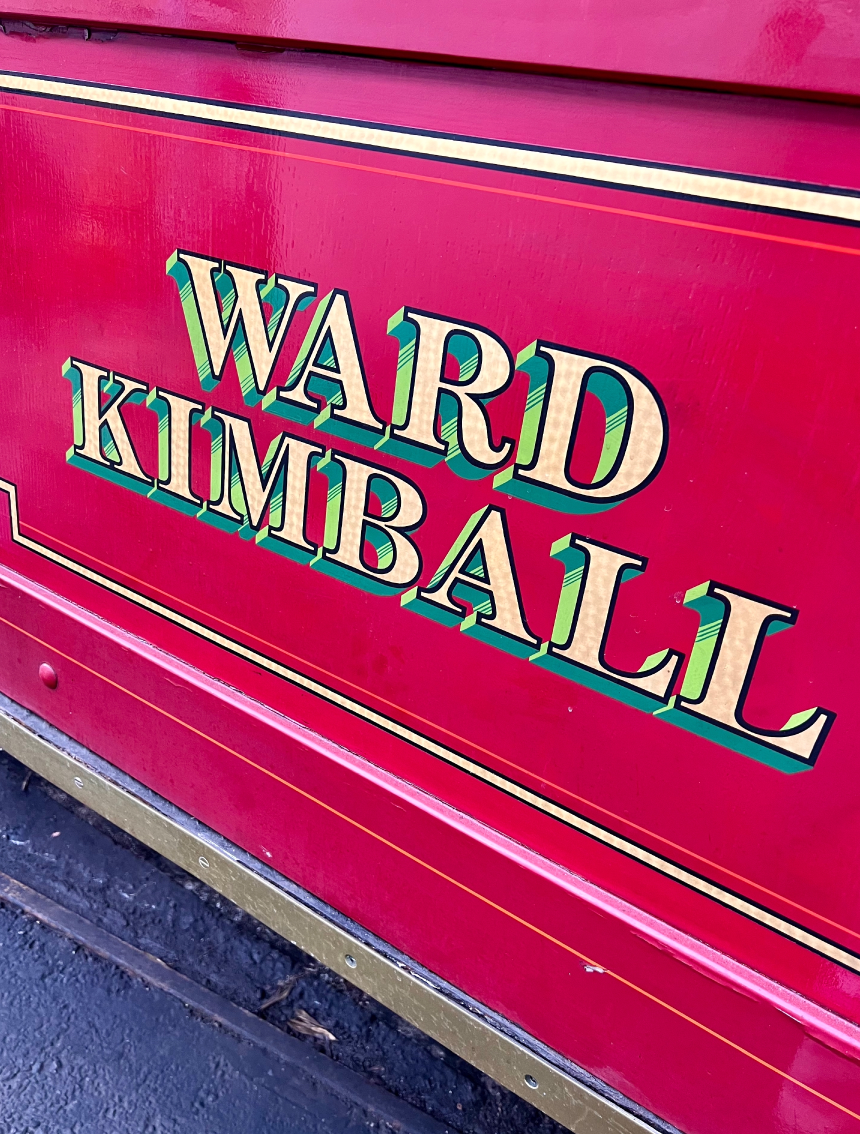 Hand-painted gilded lettering on a red rail car panel