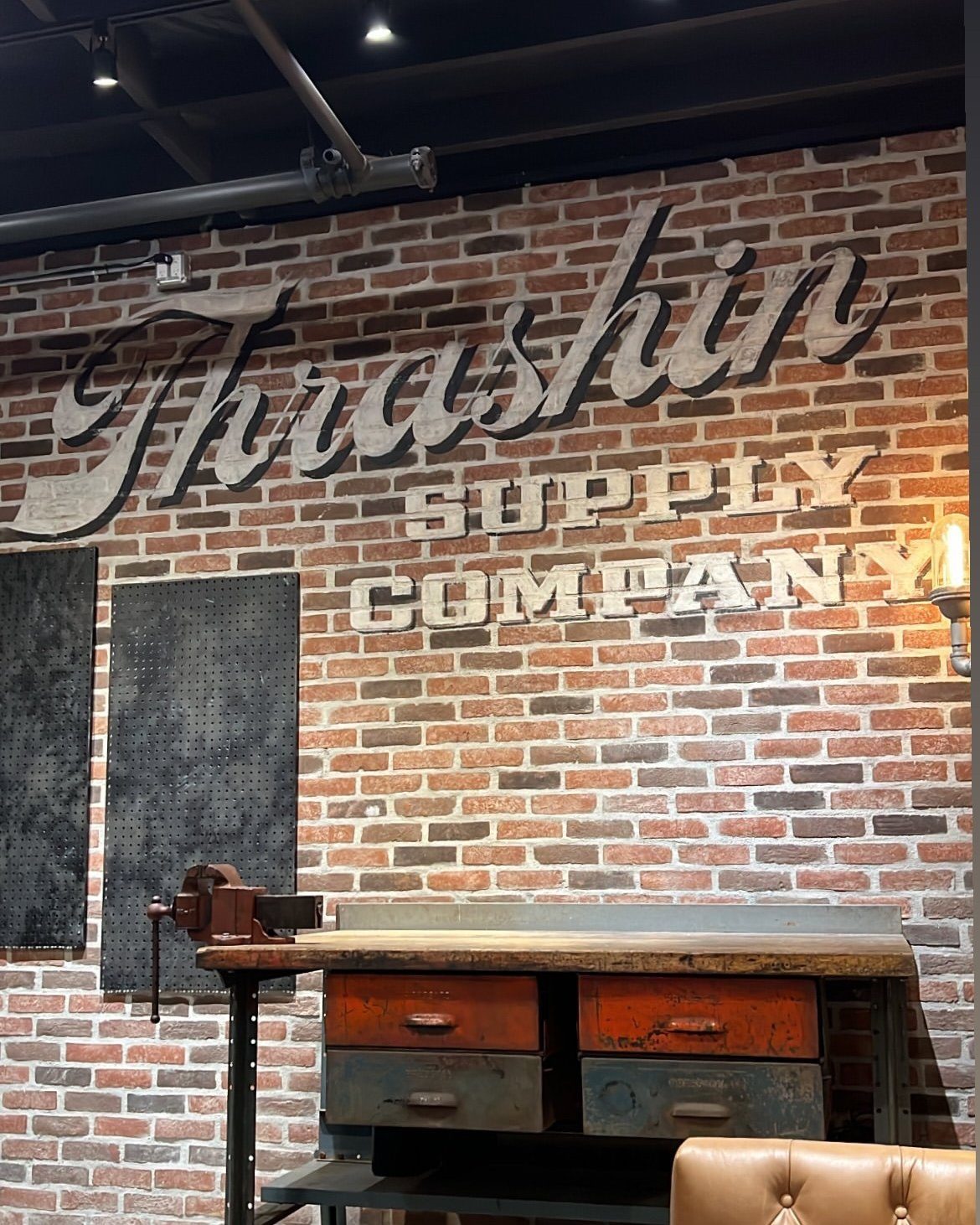 Hand-lettered script sign painted on a brick wall