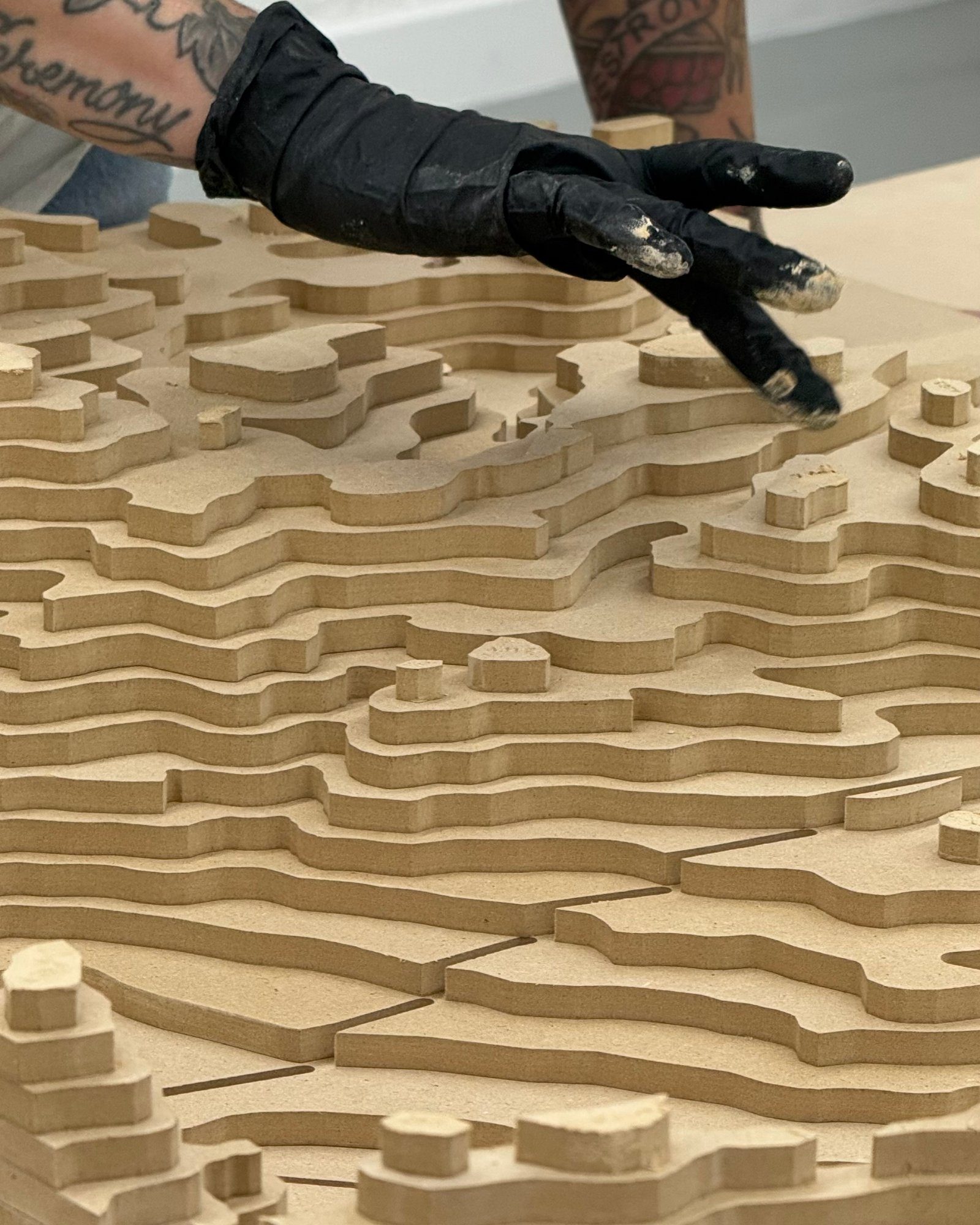 Contour-cut stacked terrain being hand finished after routing