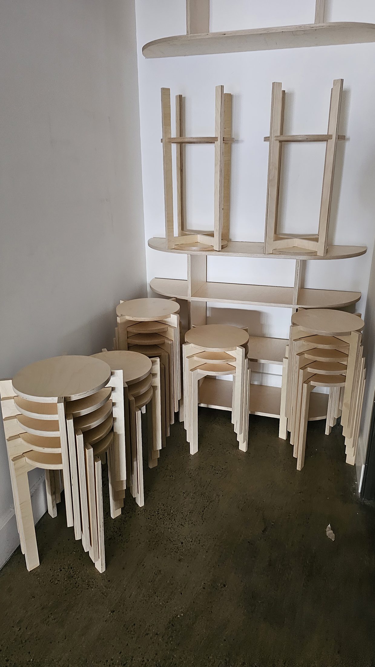 Routed plywood stools stacked against a wall