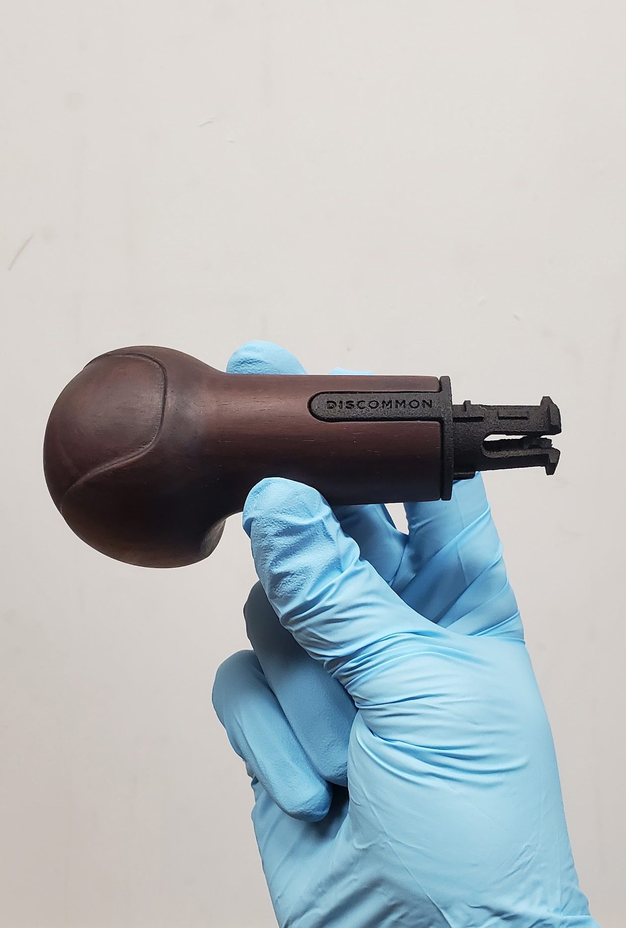Carved walnut knob held in a gloved hand