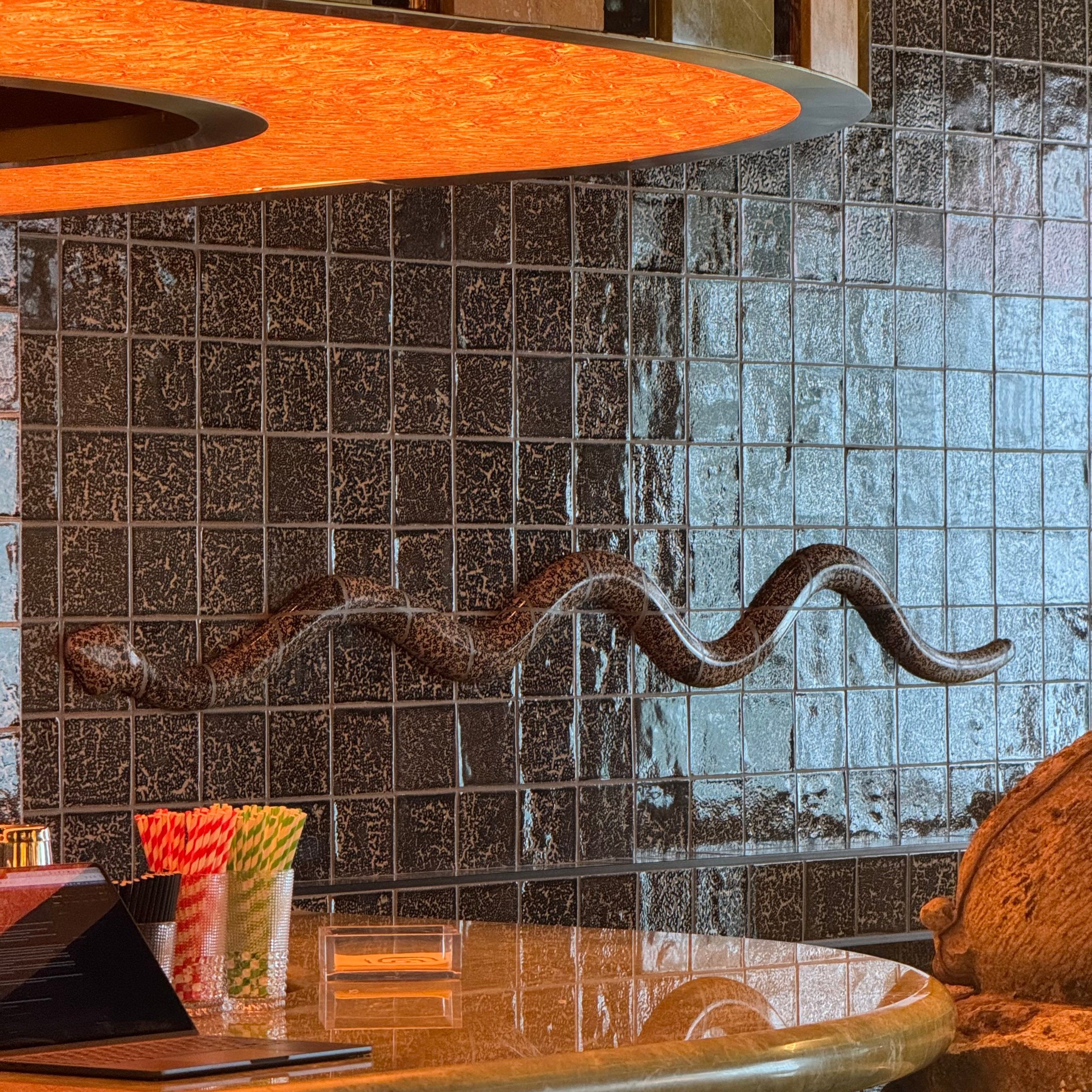 Carved serpent wall feature on glazed tile behind a restaurant bar