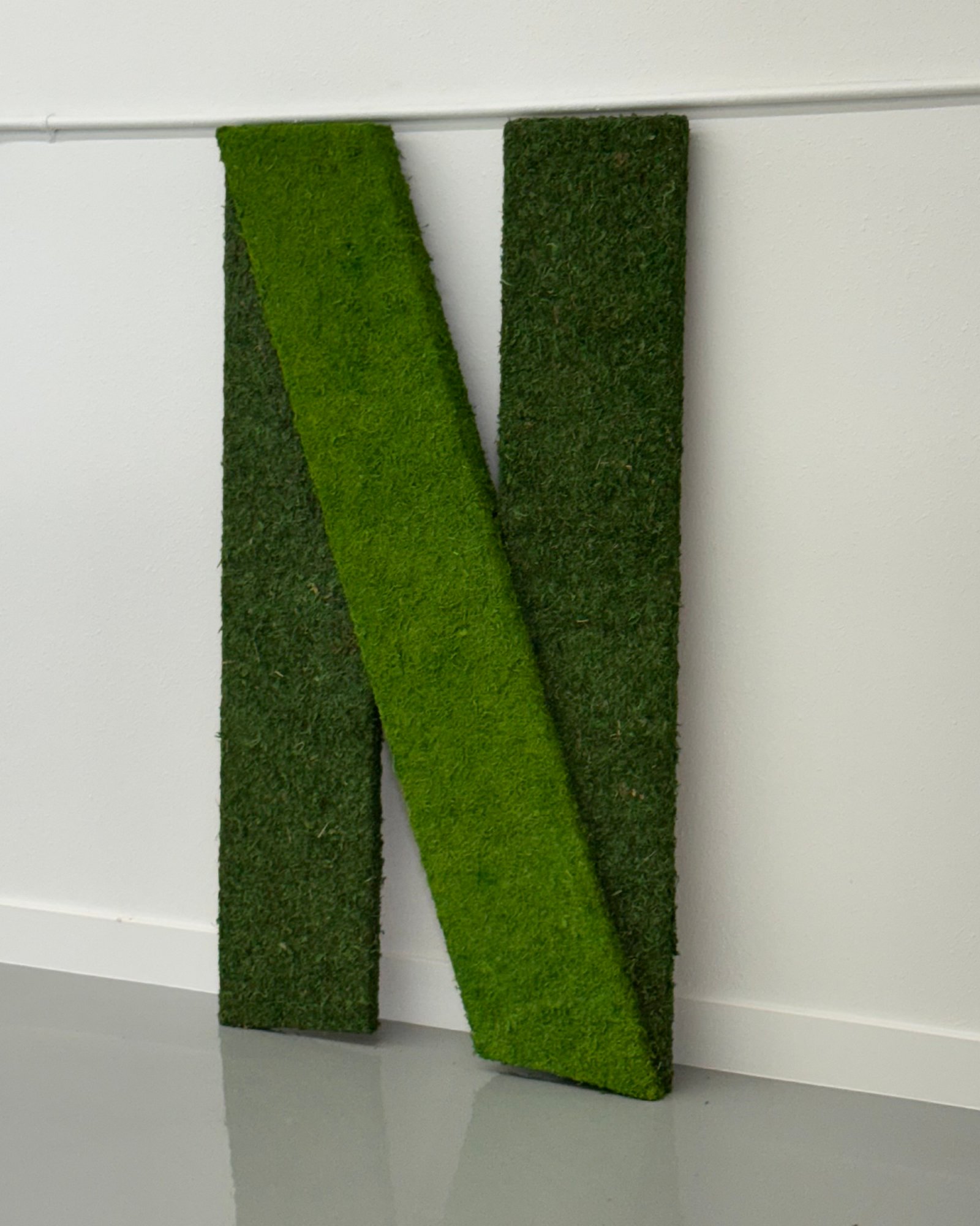Oversized moss-covered letter brand element