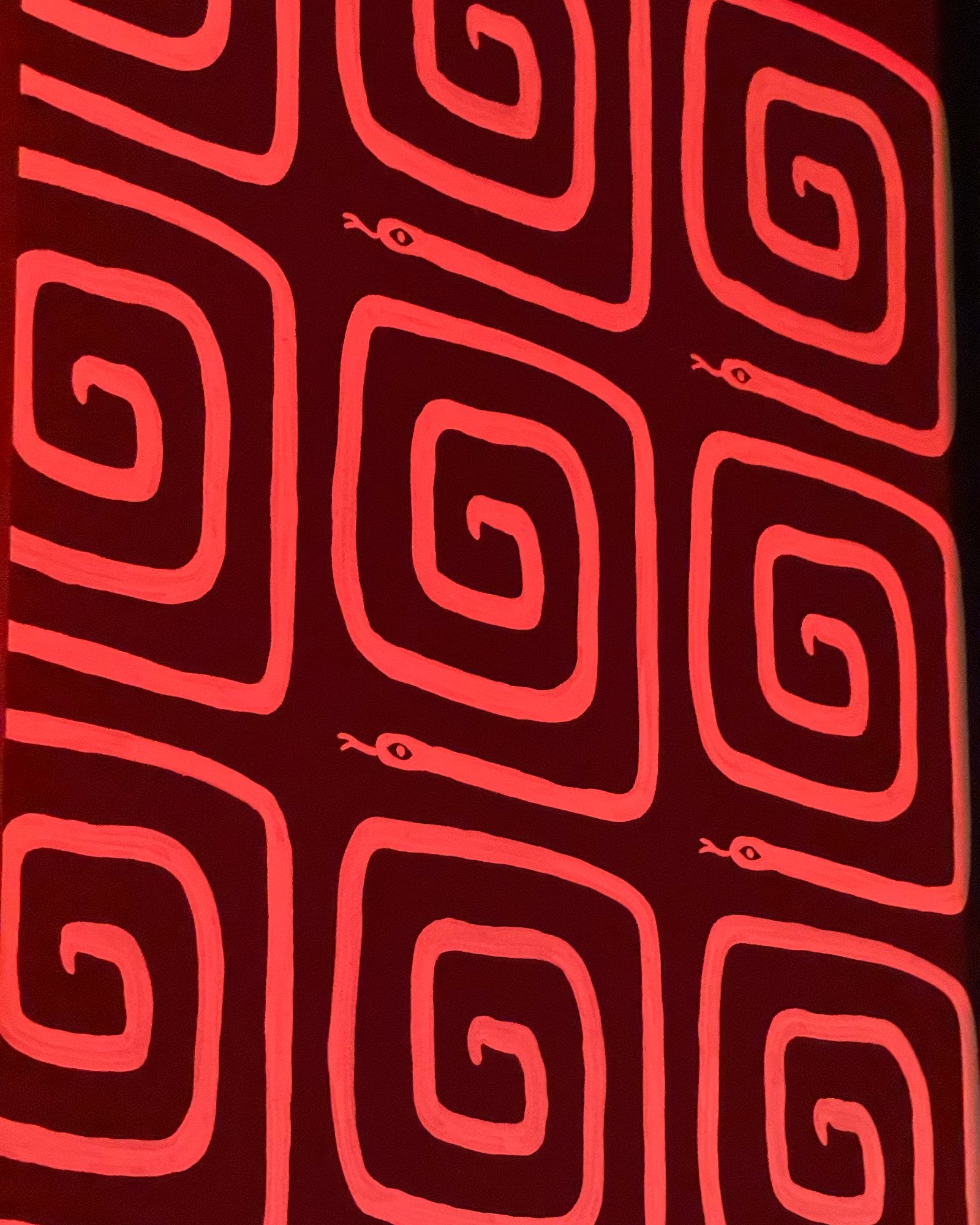 Hand-painted coral serpent spiral pattern on a red wall
