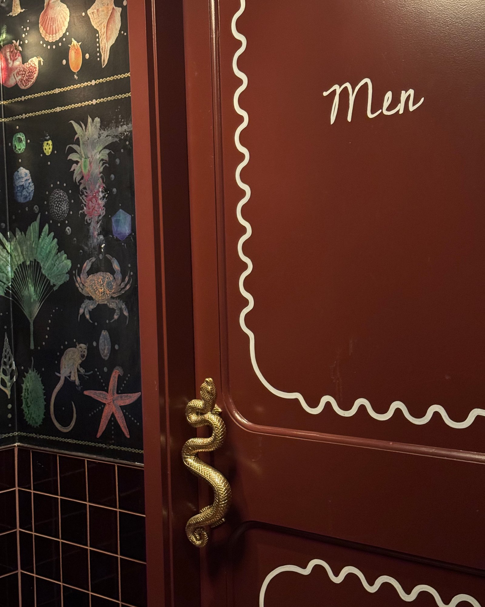 Hand-lettered door with wave linework and a brass serpent handle