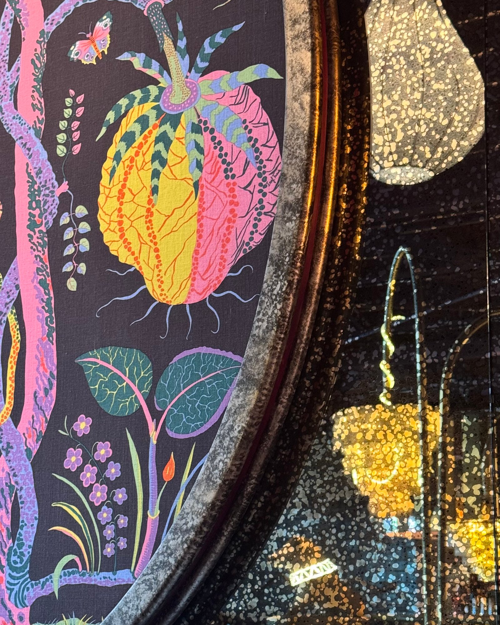 Detail of a painted floral oval panel with speckled metallic wall finish