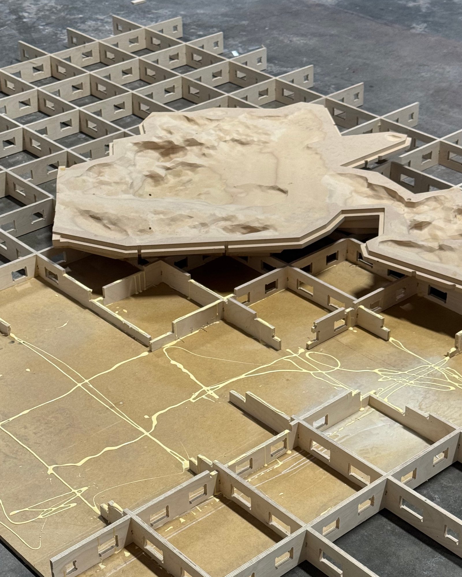 CNC-cut slotted grid base supporting sculpted terrain forms