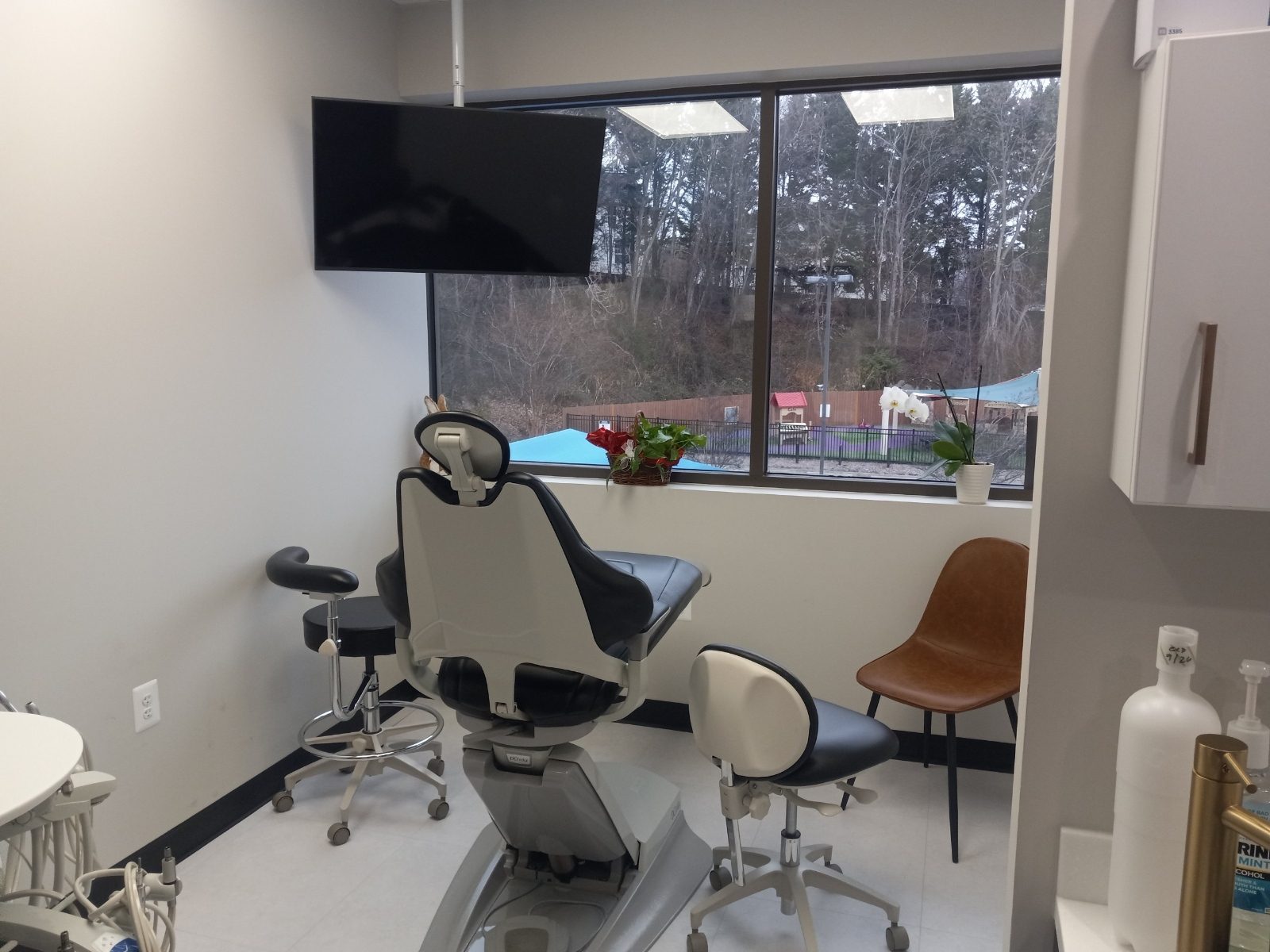 Bright dental treatment room with a large window and wall-mounted TV at Dunbar Smile Center in Stafford, VA