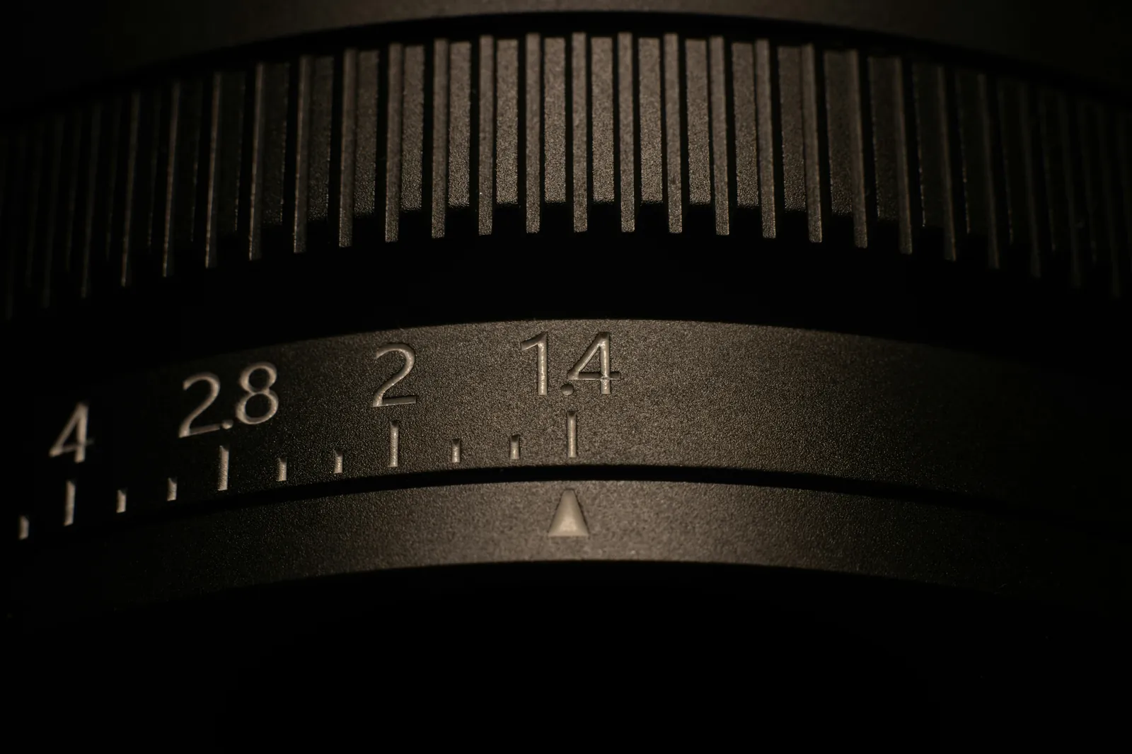 Close-up of a lens aperture ring showing f-stop markings from f/1.4 to f/4