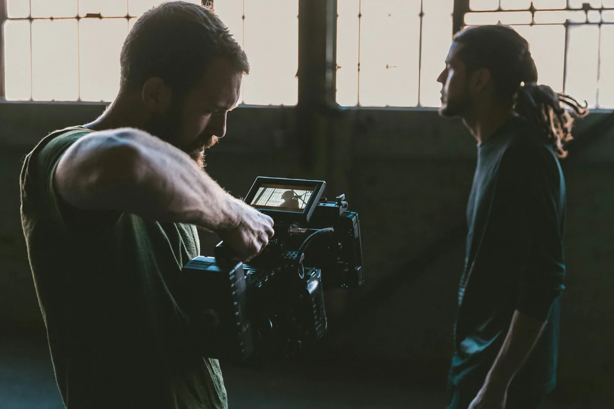 Camera operator checking a shot on the camera monitor while filming someone on set