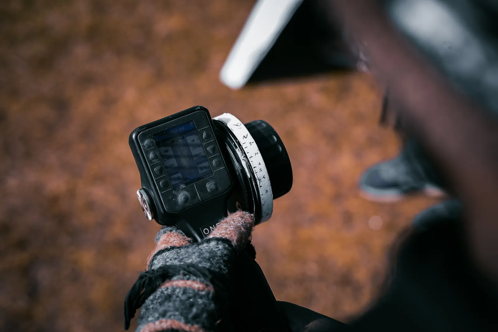 Camera assistant adjusting a wireless follow focus unit with hand-marked focus points during a shoot