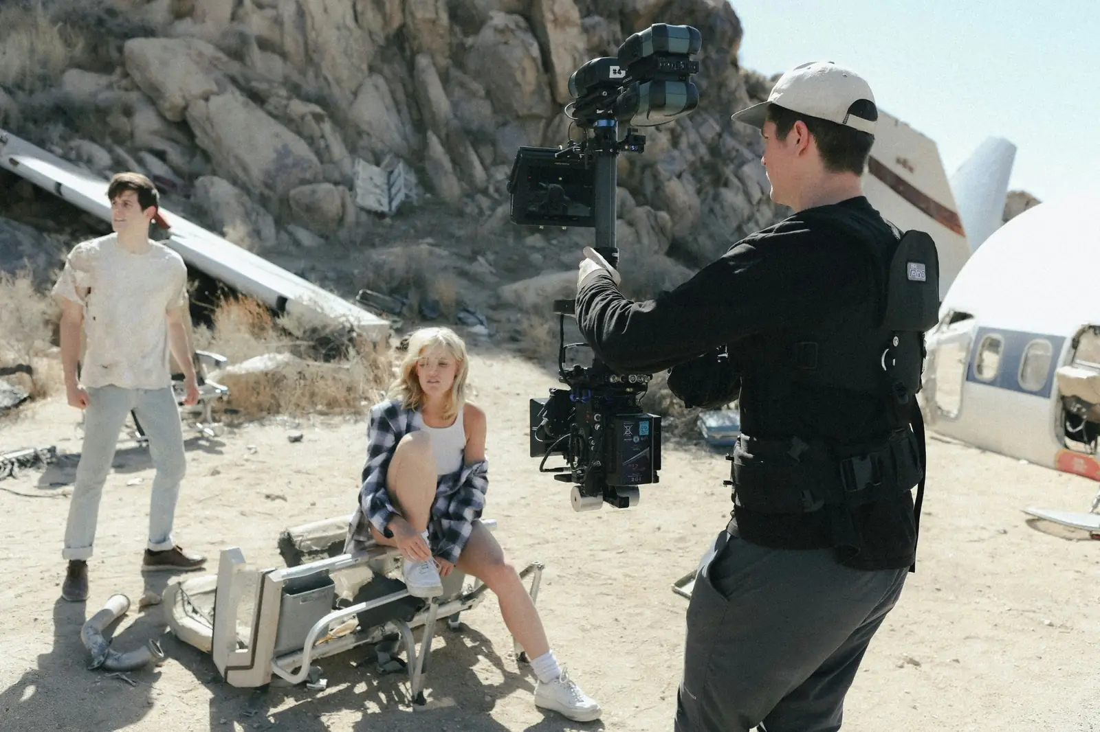 Steadicam operator filming 2 actors on a desert location beside aircraft wreckage