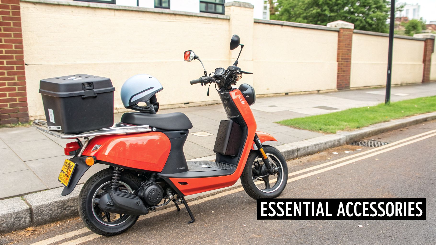 An orange electric scooter with a black storage box and light blue helmet parked on a street.