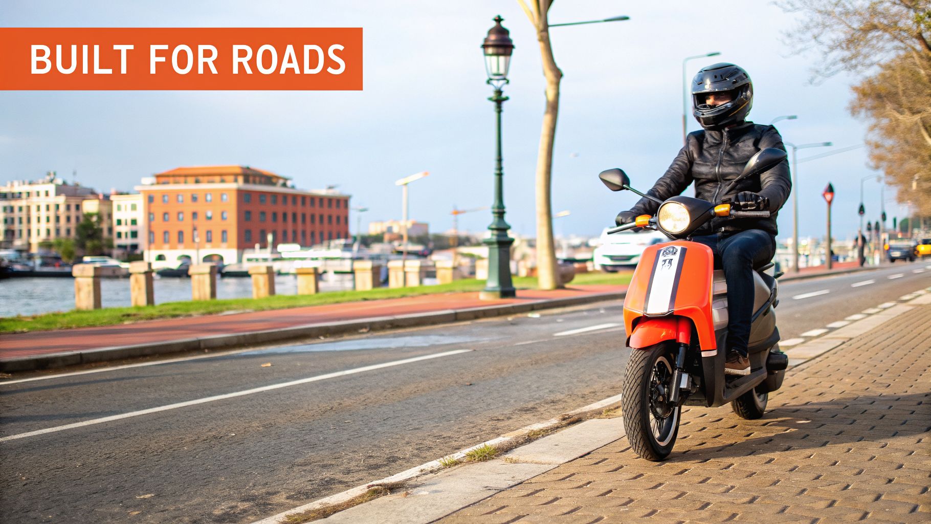 A person in a helmet rides an orange scooter on a city street next to a canal with buildings.