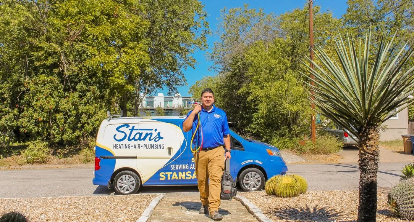 A technician from Stan's Heating, Plumbing, and Electrical walking towards a house, carrying equipment and tools, with a company van in the background, demonstrating readiness and reliability in service.