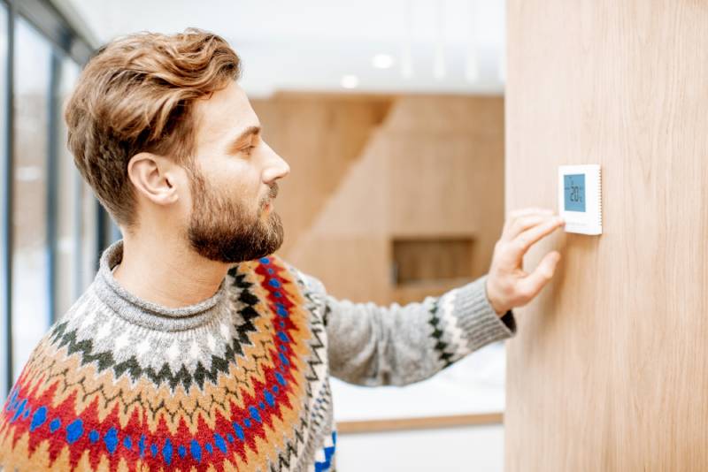 Man adjusts wall thermostat
