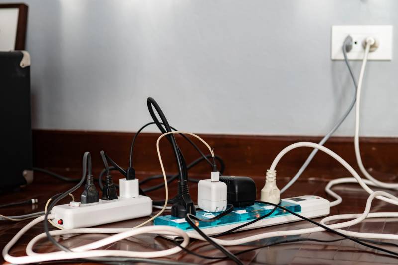 Overloaded power strips and tangled cords plugged into an outlet.