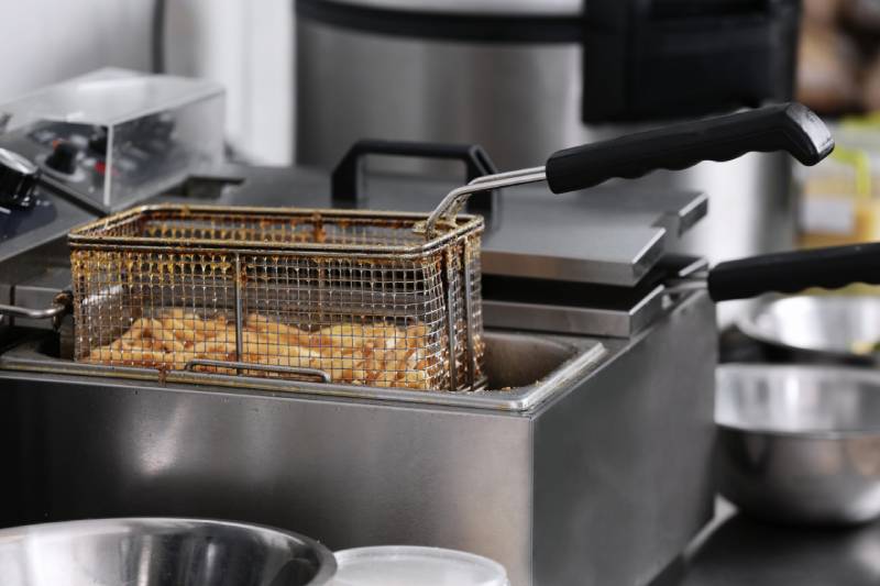 Deep fryer with basket of fries.