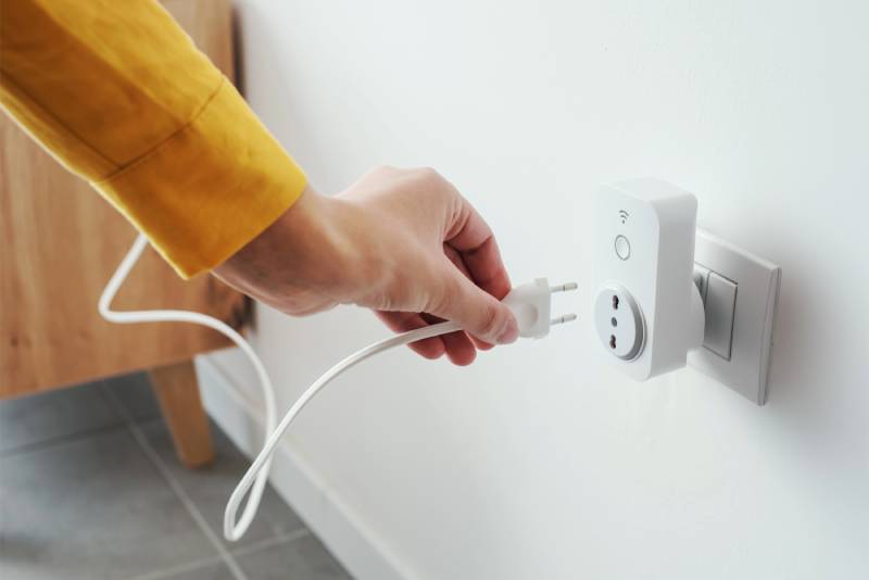 Hand plugging cord into smart outlet.
